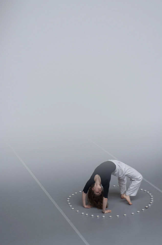  Een verticaal beeld waarvan 2/3 een witte waas in degradé over de foto loopt onderaan staat een meisje in brug omringd door een cirkel van kaarsjes.