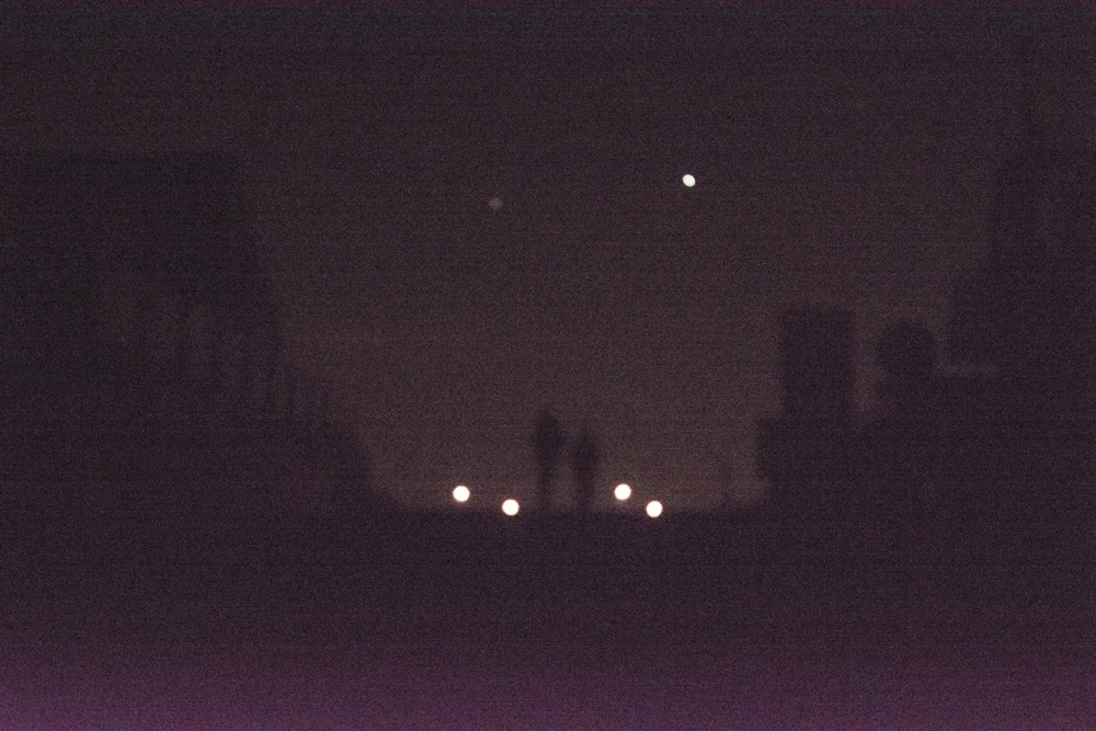  silhouetten van gebouwen en twee personen in de nacht.
                    class=
