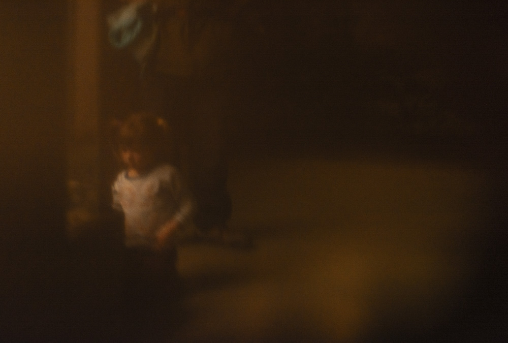 liggend beeld van een klein meisje dat naar vitrine kijkt, achter haar staat het gestalte van een volwassen man.
