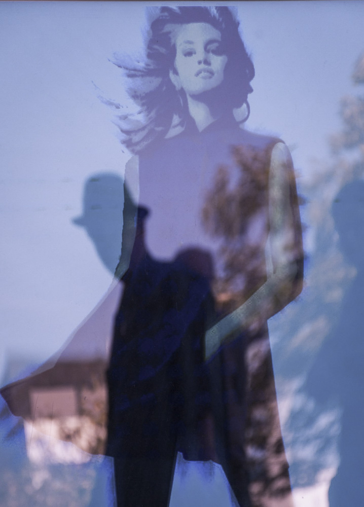 verticaal beeld van een silhouet van man met hoed gereflecteerd in een afbeelding van een jonge vrouw.